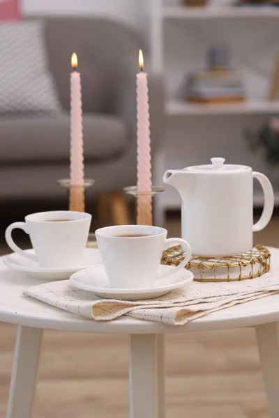 Kubki Herbaty Czajniczek Płonące Świece Białym Stoliku Kawy Pomieszczeniach — Zdjęcie stockowe
