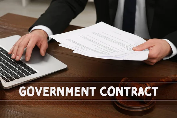 Government contract. Man reading document at wooden table, closeup