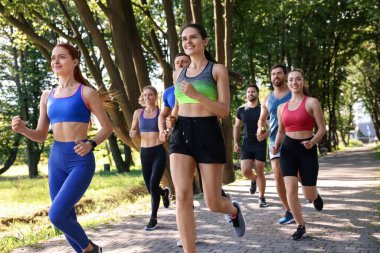 Güneşli bir günde parkta koşan bir grup insan