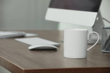 İş yerindeki ahşap masada beyaz seramik bardak. Tasarım için model