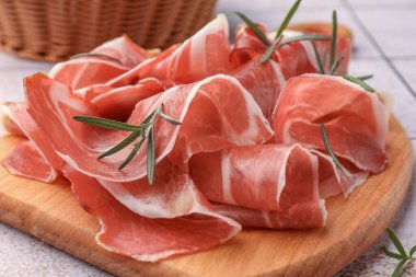 Ahşap tahtada lezzetli jambon ve biberiye dilimleri, yakın plan.