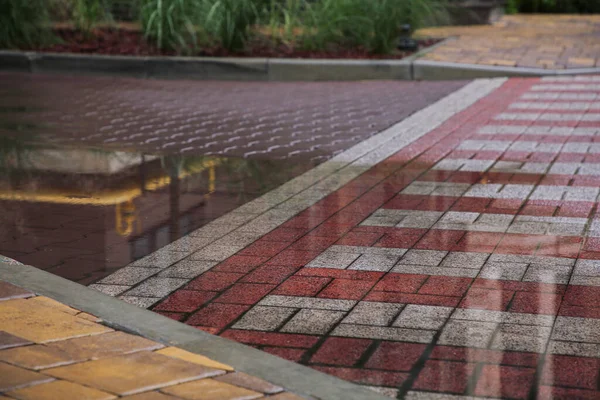 屋外の通りタイルに雨が降った後のプードル — ストック写真