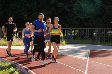 Güneşli bir günde stadyumda koşan bir grup insan. Metin için boşluk