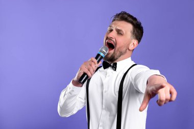 Mikrofonlu yakışıklı adam menekşe arka planda şarkı söylüyor. Metin için boşluk