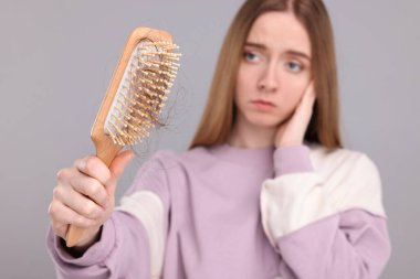 Açık gri arka planda saçları dökülmüş bir kadın, seçici bir odak noktası. Alopecia sorunu