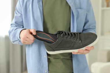 Ortopedik tabanı ayakkabının içine koyan adam, yakın plan.