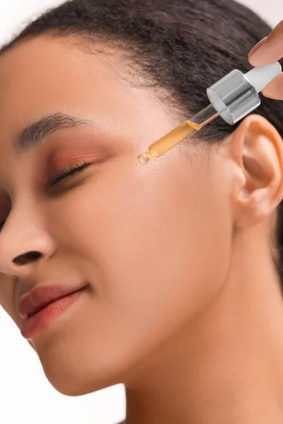 Woman applying serum onto her face, closeup