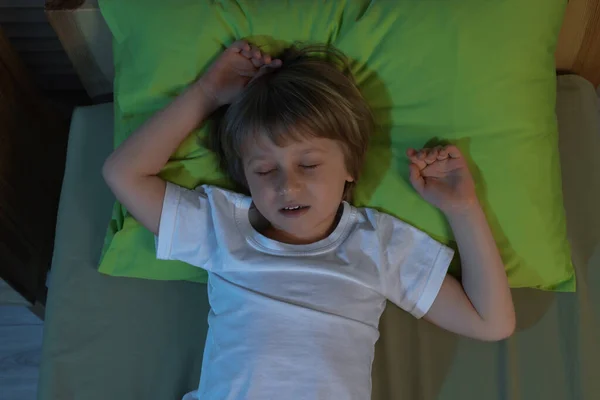 Pieni Poika Kuorsaa Nukkuessaan Sängyssä Yöllä Ylhäältä — kuvapankkivalokuva