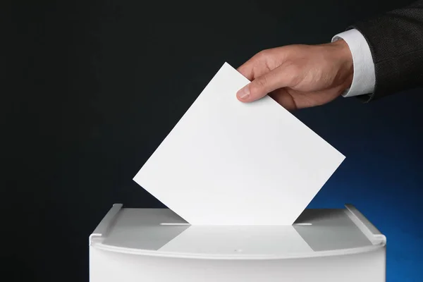 ダークブルーの背景に投票ボックスに投票する男 クローズアップ — ストック写真