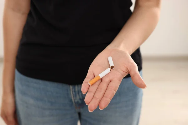 Stop smoking concept. Woman holding broken cigarette on beige background, closeup