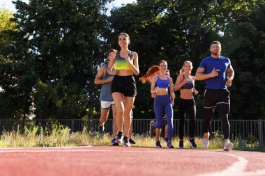 Güneşli bir günde stadyumda koşan bir grup insan. Metin için boşluk