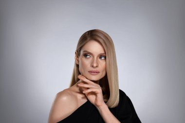 Beyaz arka planda sarı saçlı şık ve çekici bir kadının portresi.