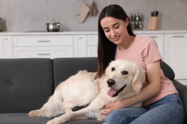 Evdeki kanepede sevimli Labrador Retriever köpeği olan mutlu kadın. Sevimli hayvan.