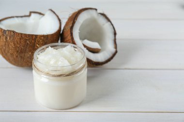 Kavanoz dolusu organik hindistan cevizi pişirme yağı ve beyaz ahşap masada taze meyveler, yazı için yer.