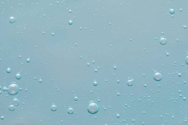 Tozlu açık mavi arka planda şeffaf temizlik jeli, üst manzara. Kozmetik ürünü