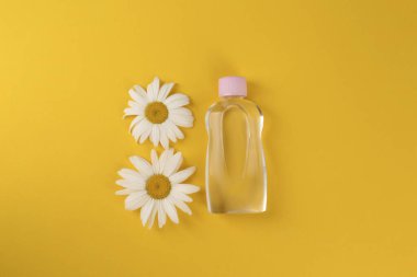 Bebek yağı şişesi ve turuncu arka planda papatyalar.