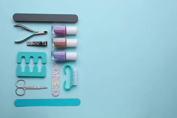 Set of pedicure tools on light blue background, flat lay. Space for text