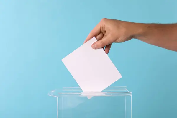 男子把他的选票放在投票箱浅蓝色背景 — 图库照片