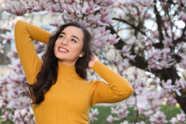 Bahar günü çiçek açan manolya ağacının yanında güzel bir kadın.