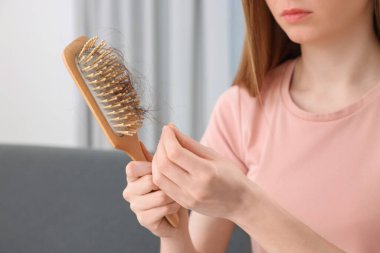 Kadın saçlarını içeride fırçalarken çözüyor, yakın plan. Alopecia sorunu