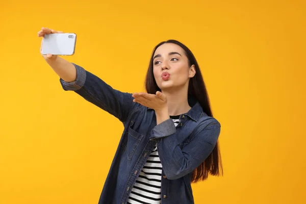 Νεαρή Γυναίκα Λήψη Selfie Smartphone Και Φυσώντας Φιλί Στο Κίτρινο — Φωτογραφία Αρχείου