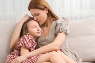 Anne ve tatlı kızı evdeki kanepede.
