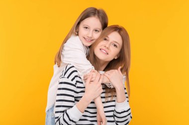 Turuncu arka planda mutlu anne ve tatlı kızının portresi.