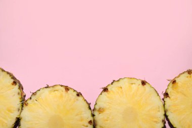 Pembe arka planda leziz olgun ananas dilimleri. Metin için boşluk