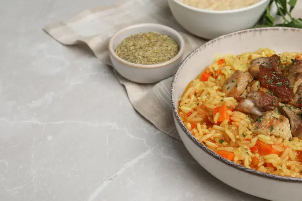 Delicious pilaf with meat and carrot on light grey table, closeup. Space for text