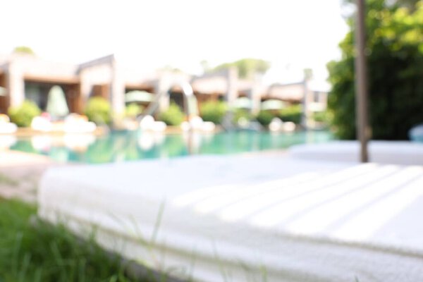 Sun loungers near outdoor swimming pool, blurred view. Luxury resort