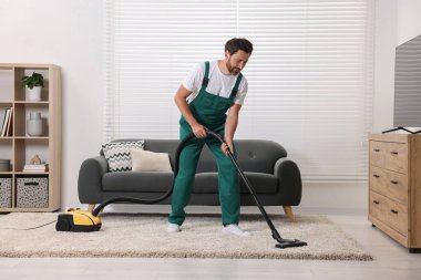 Kuru temizlemeci çalışanı, süpürgeyle halı süpürüyor.
