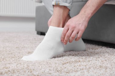 Adam evde beyaz çorap giyiyor, yakın plan.