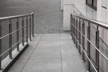 Dışarıdaki binanın yanında metal parmaklıkları olan bir rampa.