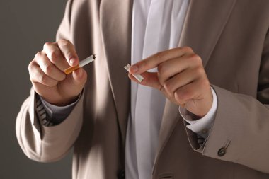 Sigara içmeyi bırak. Kırık sigara parçalarını arka planda tutan adam, yakın plan.