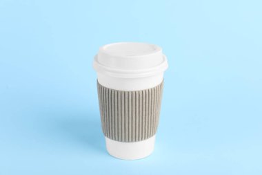 Açık mavi arka planda plastik kapaklı kağıt bardak. Kahve hazır.