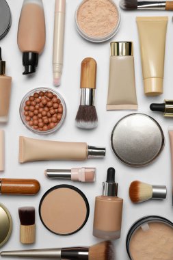 Beyaz arka planda yüz pudraları ve diğer makyaj ürünleri, düz yatıyordu