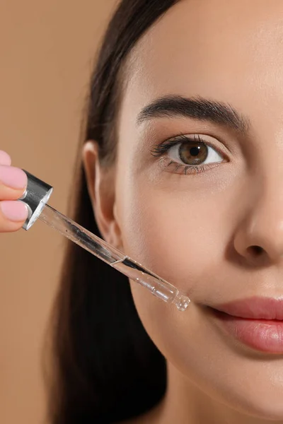 Beautiful Young Woman Applying Serum Her Face Beige Background Closeup — Stock Photo, Image