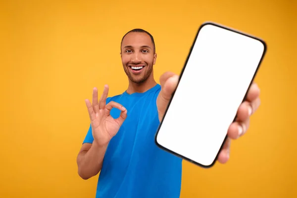 Mladý Muž Ukazuje Smartphone Ruce Gesto Žlutém Pozadí — Stock fotografie