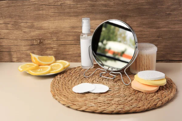 Lemon face cleanser. Fresh citrus fruits, personal care products and mirror on beige table