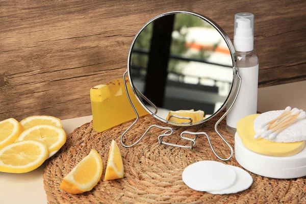 Lemon face cleanser. Fresh citrus fruits, personal care products and mirror on beige table