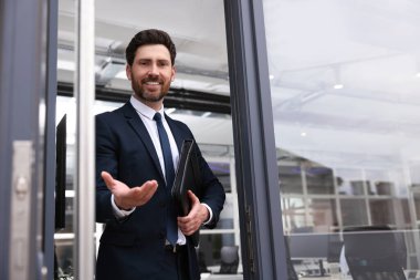 Deri portföylü erkek emlakçı içeri davet ediyor.