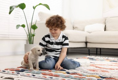 Evdeki halıda sevimli köpek yavrusu olan küçük çocuk.