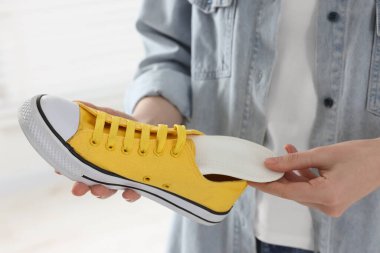 Kadın, arka planda bulanık bir şekilde ortopedik tabanı ayakkabıya yerleştiriyor. Yakın plan. Ayak bakımı