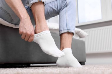 Adam evde beyaz çorap giyiyor, yakın plan.