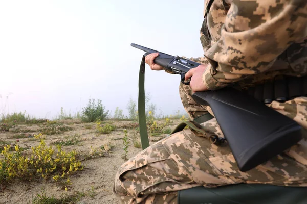 Man wearing camouflage with hunting rifle outdoors, closeup. Space for text