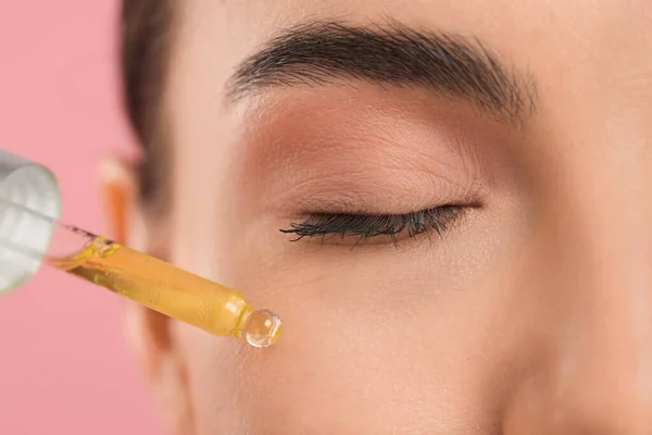 Young Woman Applying Serum Her Face Pink Background Closeup — Stock Photo, Image