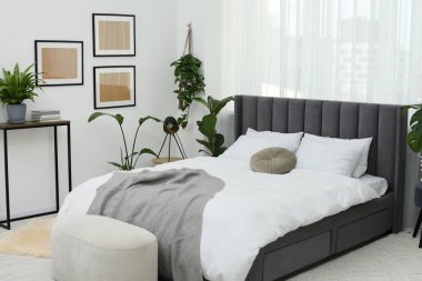 Büyük, rahat bir yatak ve güzel bitkiler. Yatak odasının içi.