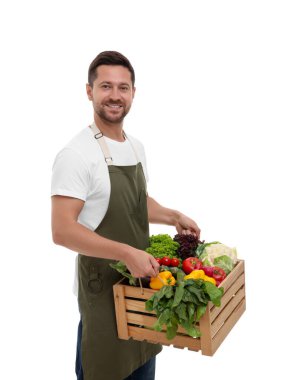 Hasat mevsimi. Beyaz arka planda sebzeli ahşap sandık tutan mutlu çiftçi.