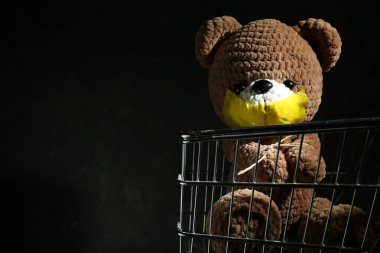 Çocuk istismarını durdurun. Siyah arka planda ağzı bantlı oyuncak ayı, yakın plan. Metin için boşluk