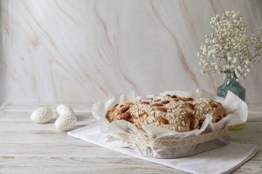 Lezzetli İtalyan Paskalya güvercini pastası (geleneksel Colomba di Pasqua), beyaz ahşap masa üzerinde süslü yumurta ve çiçekler. Metin için boşluk